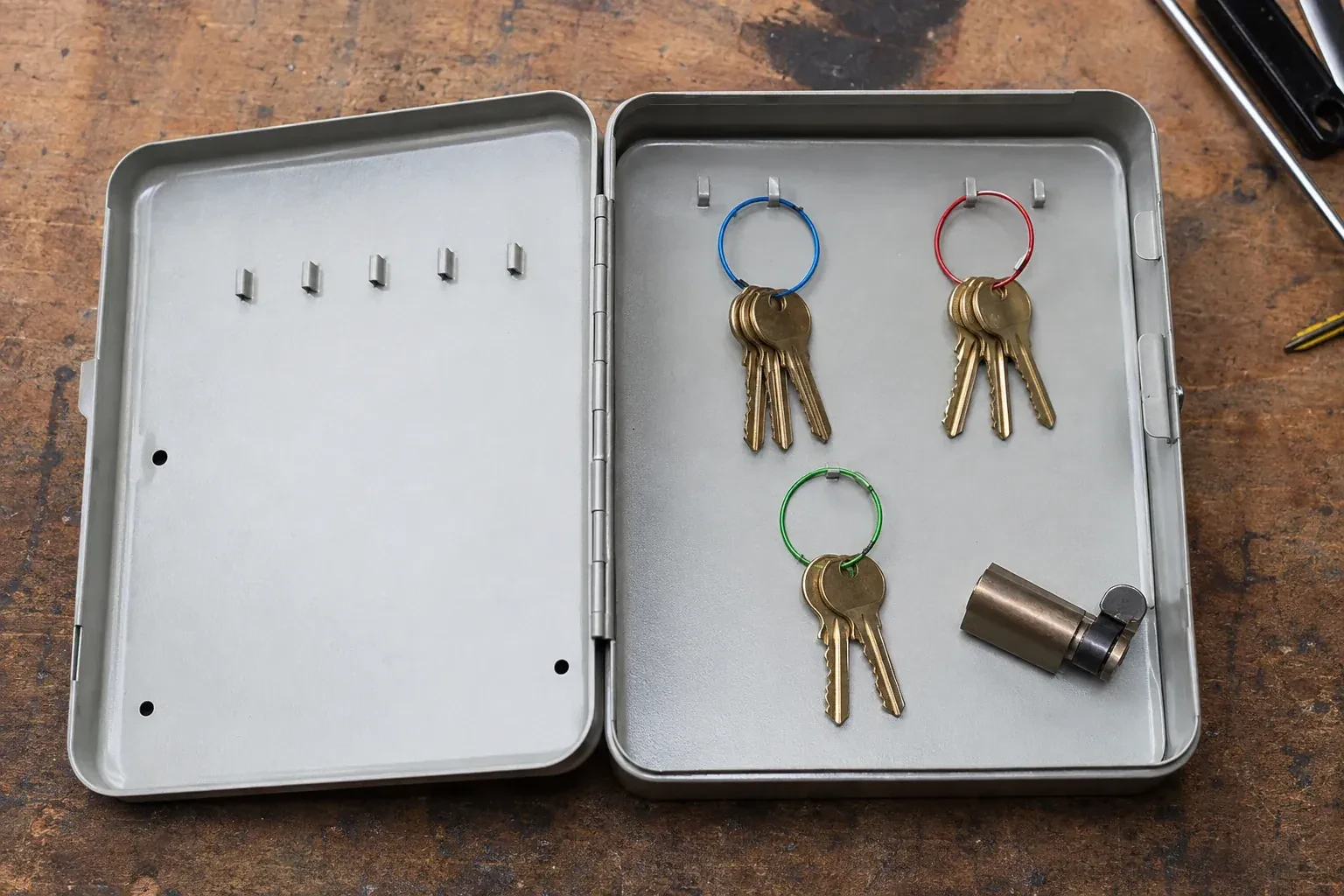 Three groups of keys on colored rings in an open metal key cabinet. — Master Key System Design, Oshawa